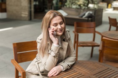  elinde bir telefon ile bir masada oturan kız