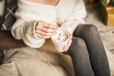 genç kadın bir ekose bir fincan kakao ve şekerleme ile oturur