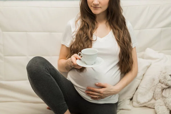 Femeie gravidă pe canapea cu ceașcă de ceai — Fotografie, imagine de stoc