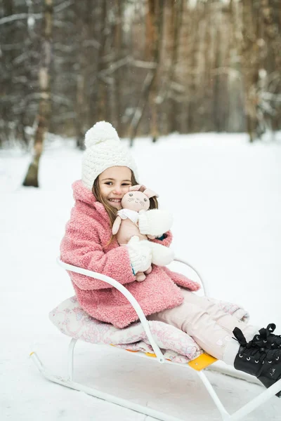 Kleines Mädchen auf Schlitten im Wald — Stockfoto