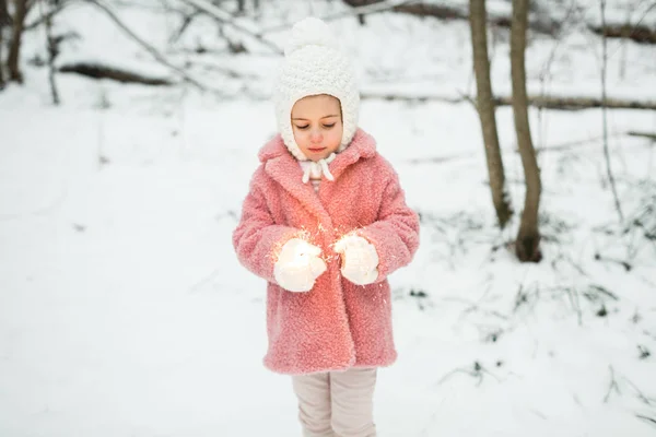 Dziewczynka trzyma bengal światła zimą w lesie — Zdjęcie stockowe