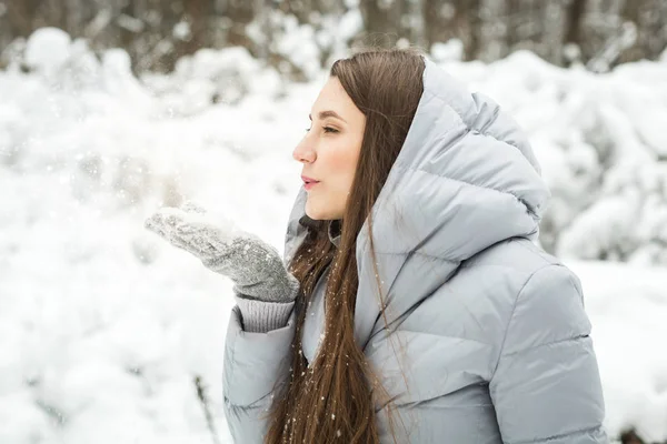 Mladá žena zimní portrét. Zimní žena foukání sníh v lese — Stock fotografie