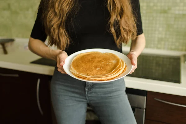 The woman is standing with pancakes in the kitchen — Stock Photo, Image