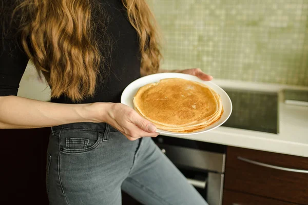The woman is standing with pancakes in the kitchen — Stock Photo, Image