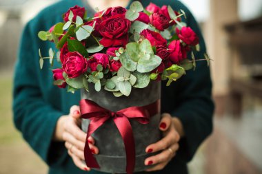 Kız onun elinde bir buket kırmızı gül tutan