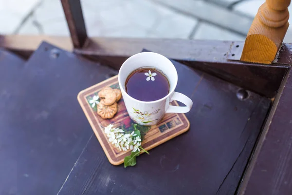 A cup of tea and biscuits on the porch of a wooden house in vill — Stock Photo, Image