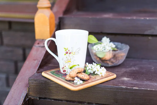 A cup of tea and biscuits on the porch of a wooden house in vill — Stock Photo, Image