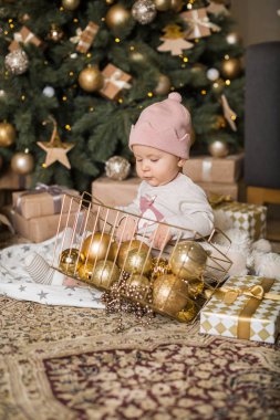 Küçük kız Noel ağacının altında oyuncaklarla oynuyor.