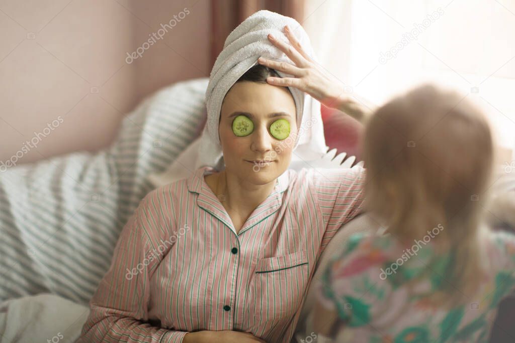 mother with daughter, mother with cucumbers in front of her, home spa concept