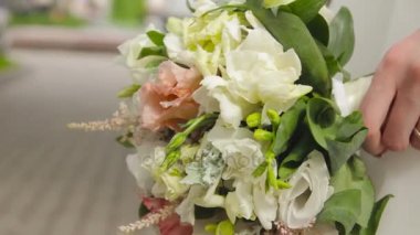 Beyaz gelinlik giymiş genç gelinin elinde güzel gelin buketi.