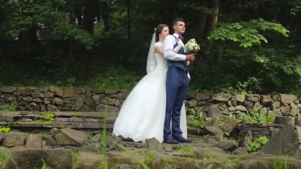 Невеста, стоящая за женихом и обнимающая его — стоковое видео