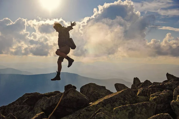 Caminante con mochila saltando sobre rocas puesta del sol cielo en el fondo Fotos De Stock Sin Royalties Gratis