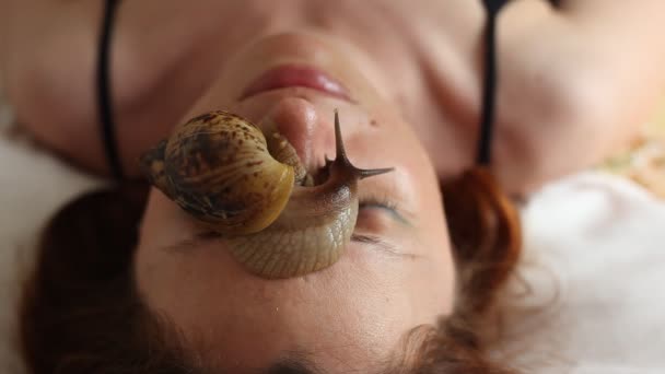 Молода жінка у спа-центрі отримує масаж обличчя з африканських равликів Achatina. Равлики їдять мертвих шкіру від тих, що випускається. Зрештою вона залишає шкіру гладкою і свіжі. — стокове відео