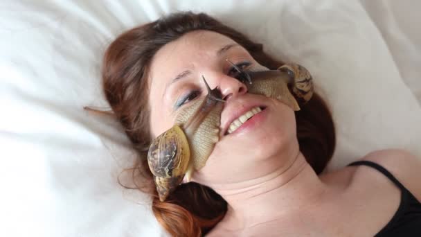 Une jeune femme au spa reçoit un massage facial avec des escargots africains Achatina. Les escargots mangent la peau morte des produits. Au final, il laisse la peau lisse et fraîche . — Video