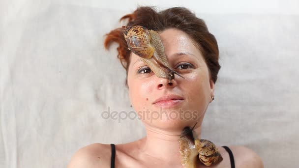 Młoda kobieta w spa odbiera masaż twarzy z Afryki ślimaki Achatina. Ślimaki jeść martwy naskórek od tych produkowanych. W końcu pozostawia skórę gładką i świeżą. — Wideo stockowe