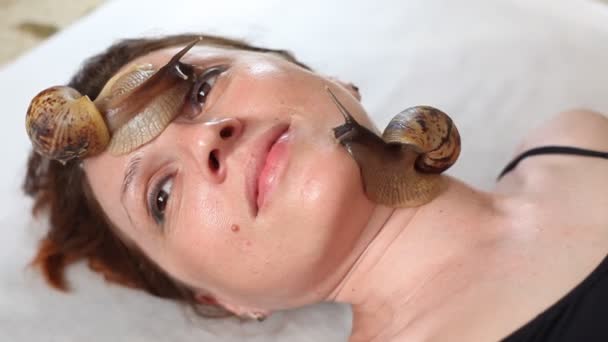 Une jeune femme au spa reçoit un massage facial avec des escargots africains Achatina. Les escargots mangent la peau morte des produits. Au final, il laisse la peau lisse et fraîche . — Video