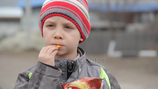 Menino na aldeia a comer batatas fritas — Vídeo de Stock