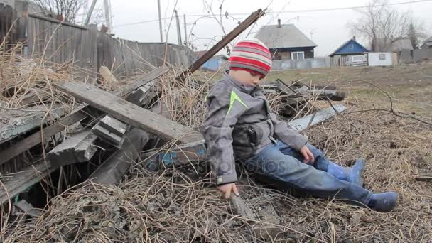 Der Junge spielt seit vier Jahren auf den Ruinen eines alten Holzhauses — Stockvideo