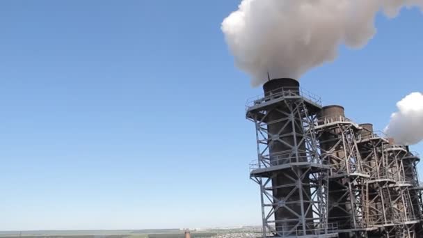 Witte rook komt uit de fabriek leidingen tegen de blauwe hemel — Stockvideo
