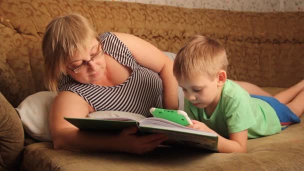 Женщина Ребенком Читает Книгу Лежащую Диване — стоковое видео