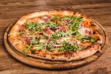 Etli pizza, pastırma, ahşap arka planda roka.