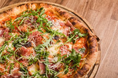 Etli pizza, pastırma, ahşap arka planda roka.