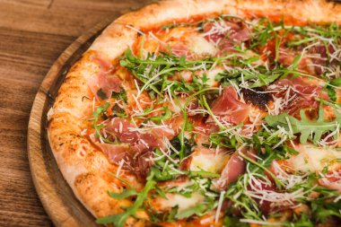 Etli pizza, pastırma, ahşap arka planda roka.