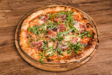 Etli pizza, pastırma, ahşap arka planda roka.