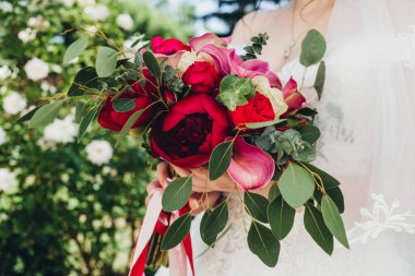 Düğün resmi ve kırmızı çiçekli bir gelin buketi.