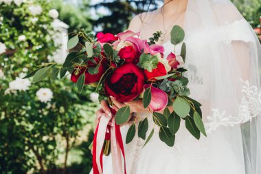 Düğün resmi ve kırmızı çiçekli bir gelin buketi.