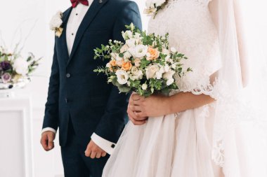 Düğün resmi ve kırmızı çiçekli bir gelin buketi.