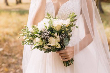 Düğün resmi ve kırmızı çiçekli bir gelin buketi.