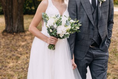 Düğün resmi ve kırmızı çiçekli bir gelin buketi.