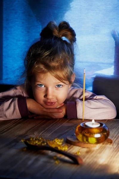 Menina de 3 crianças olhando para algo como vela acesa no castiçal. Casa calor e conforto como criança — Fotografia de Stock