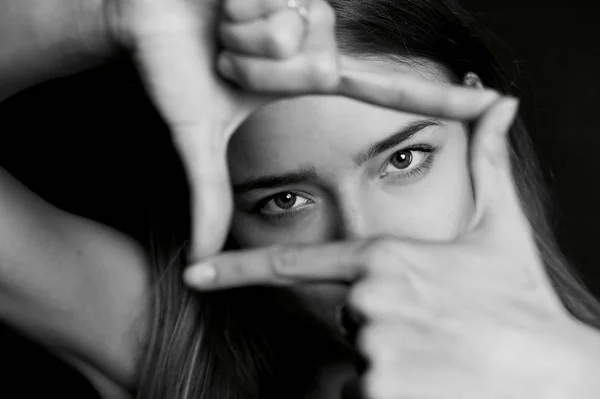 La chica con el pelo largo sosteniendo sus manos frente a mis ojos para el marco. Blanco y negro , —  Fotos de Stock