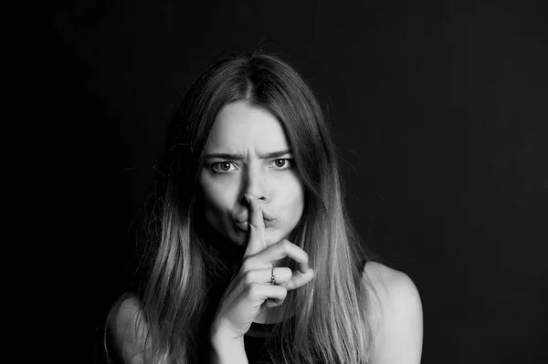 La chica con el pelo largo sostiene el dedo cerca de los labios. gesto de silencio, secreto, secreto — Foto de Stock