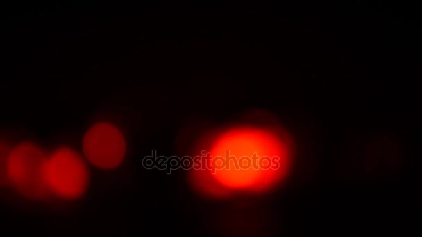 Luzes desfocadas vermelhas em um fundo escuro . — Vídeo de Stock