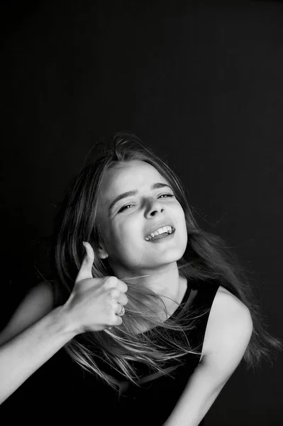 Menina bonita nova com cabelo longo no estúdio. Gesto polegar um sorriso . — Fotografia de Stock