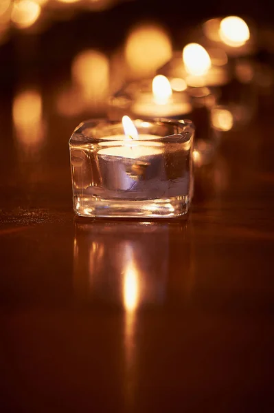 Brennende Kerzen in durchsichtigen Gläsern, glänzender Boden, das Spiegelbild. Stimmung, Entspannung, Gebet und Trost — Stockfoto