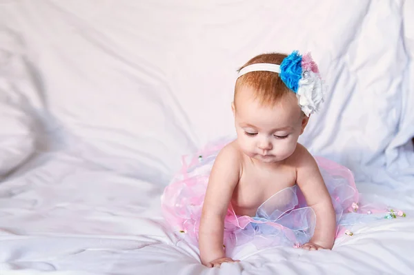 Bebé recién nacido con una corona de ganchillo blanco, tutú bailarina, y zapatillas de ballet. Ella está durmiendo en rosa rosa tela de la cinta . —  Fotos de Stock