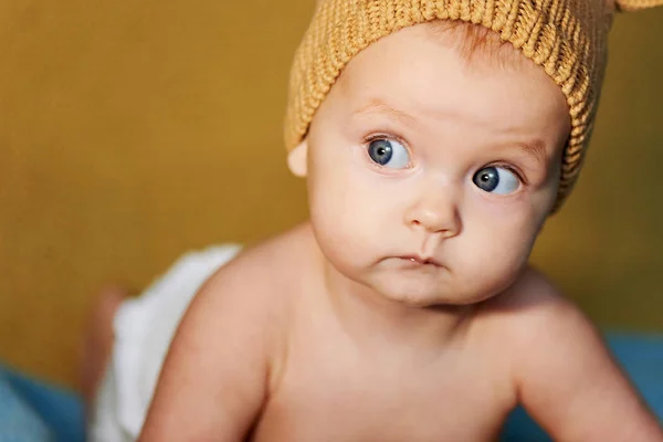 Pequeno bebê recém-nascido com grandes olhos chapéu-tricô em um fundo simples . — Fotografia de Stock