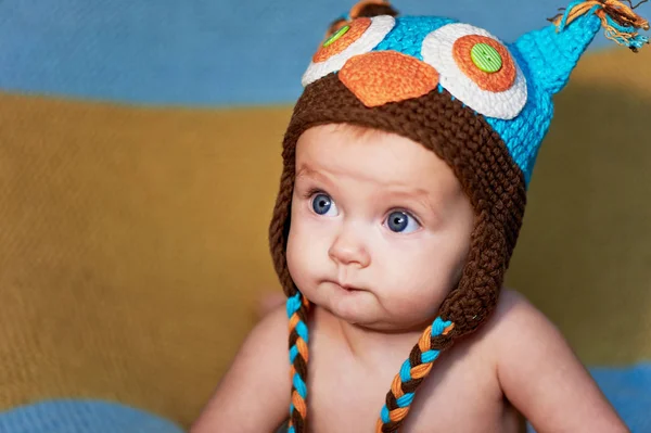 Pequeno bebê recém-nascido com grandes olhos chapéu-tricô em um fundo simples . — Fotografia de Stock