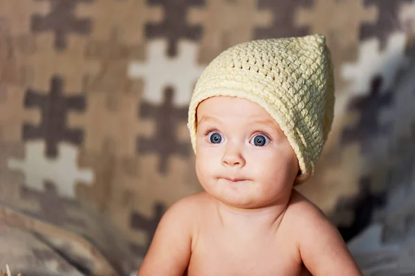 Pequeno bebê recém-nascido com grandes olhos chapéu-tricô em um fundo simples . — Fotografia de Stock