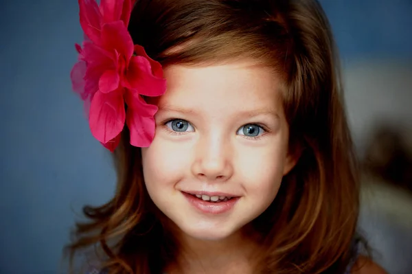 Hermosa niña con la barreta roja en forma de una flor en el cabello — Foto de Stock