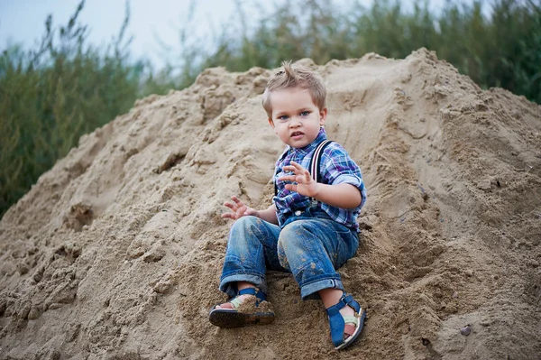 Pequeño chico lindo montando una montaña rusa de arena en la parte inferior. Recuerdos de la infancia y sin preocupaciones —  Fotos de Stock