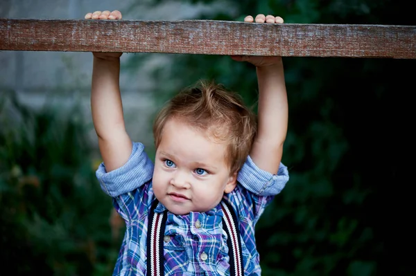 Aranyos kisfiú a keresztléc lóg. Emlékek a gyermekkor és a gondtalan — Stock Fotó