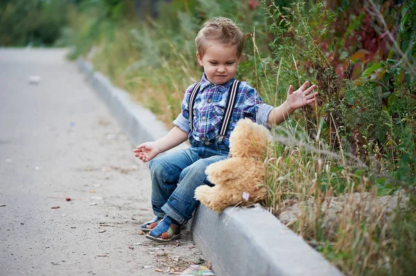 Um rapaz giro sentado no passeio e a falar com o Teddy. Memórias da infância despreocupada — Fotografia de Stock