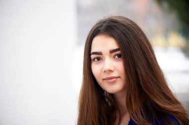Genç kız kameraya bakıyor. Uzun siyah saçlı ve kahverengi gözleri .