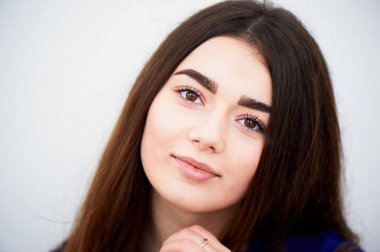 Genç kız kameraya bakıyor. Uzun siyah saçlı ve kahverengi gözleri .