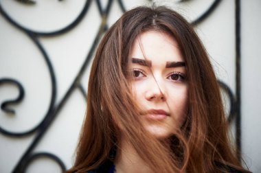 Genç kız kameraya bakıyor. Uzun siyah saçlı ve kahverengi gözleri .